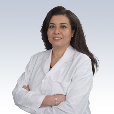 Hearing care professional in a white lab coat with arms crossed.