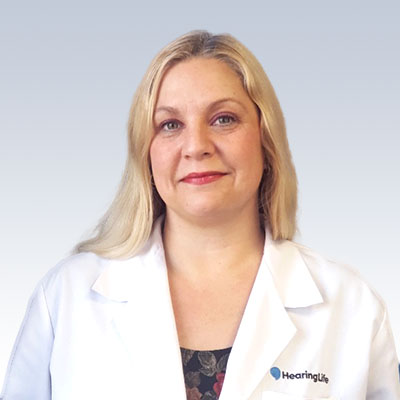 Anita Avallone wearing a white coat with the HearingLife logo.