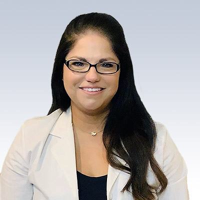 Audrey Gonzalez, hearing care specialist, wearing a white coat against a gradient background.