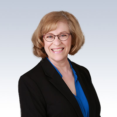 Bonni Scott in professional attire wearing a black blazer and blue blouse against a gradient background.