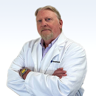 Christopher Bartlett, hearing care specialist wearing a white lab coat with arms crossed.