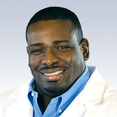 Cliff Johnson wearing a white coat with a light blue background.