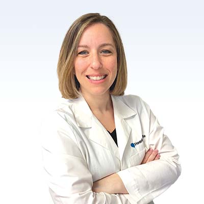 hearing care professional in a white coat with arms crossed