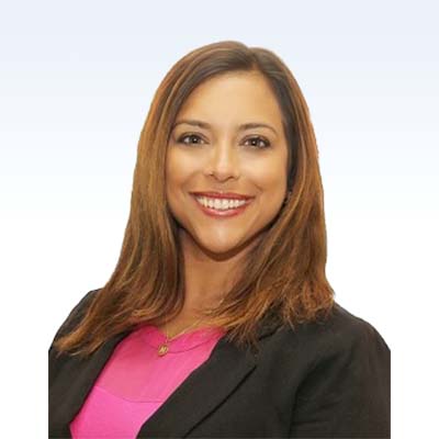 Deborah Brooks, hearing care professional, wearing a black blazer and pink top against a light background.