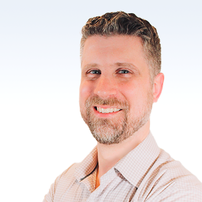 eric gilbert, hearing care specialist, wearing a light-colored checkered shirt against a gradient blue and white background