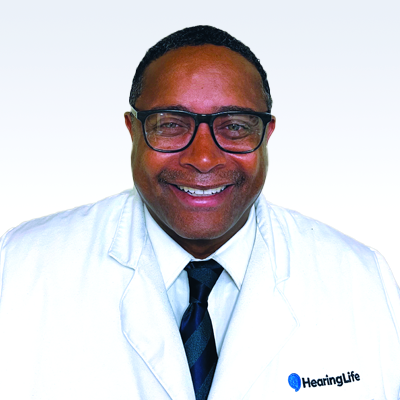 Hearing care professional Erik Buford in a white coat with a HearingLife logo.