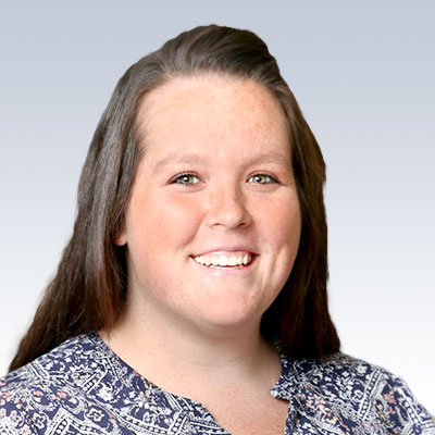 Jacey Courser, hearing care professional, wearing a patterned blouse against a gradient background.