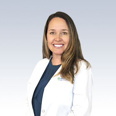 Jacquie Dannreuther wearing a white lab coat with a hearing care clinic logo.