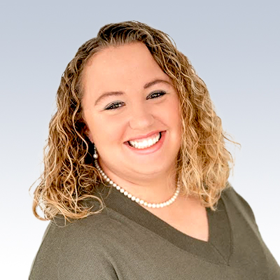 Jamie Burkholder, hearing care professional wearing a green sweater and pearl necklace.