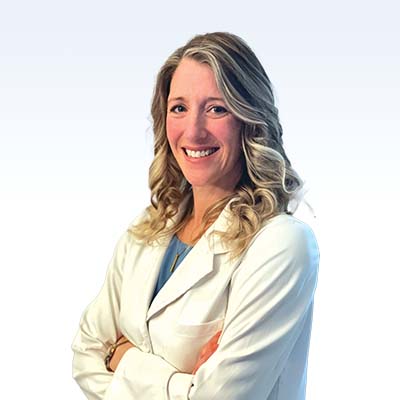 Hearing care professional in a white coat with arms crossed.