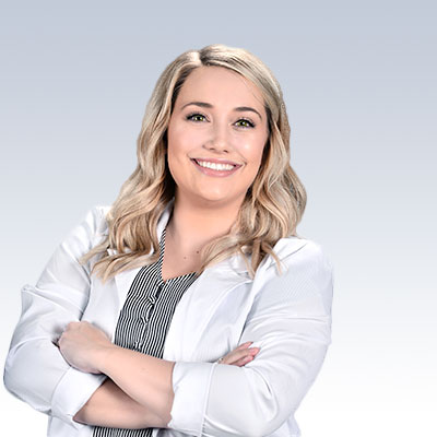 Jocelyn Motter, hearing care professional with crossed arms wearing a white coat, standing against a gradient background.