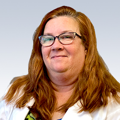 Jodi Bokan, hearing care professional with red hair, in a white coat.