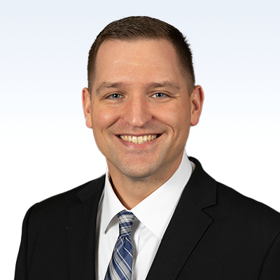 Joseph Motzko, hearing care professional, wearing a suit and tie against a light background.