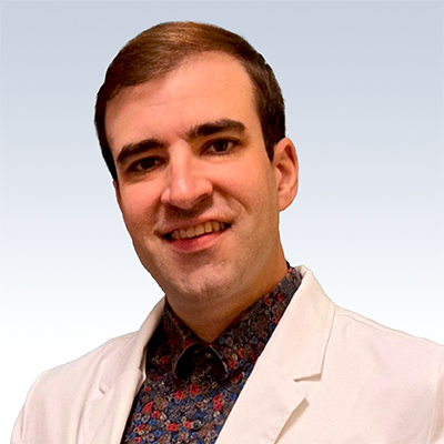 Hearing care specialist wearing a white coat against a light gradient background.