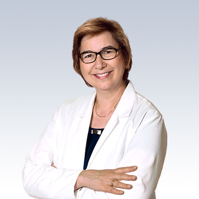 Kathleen Spilar wearing a white lab coat, representing hearing care expertise.