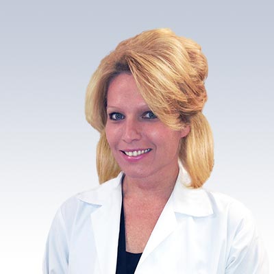 Keri Maas wearing a white lab coat against a light blue background.