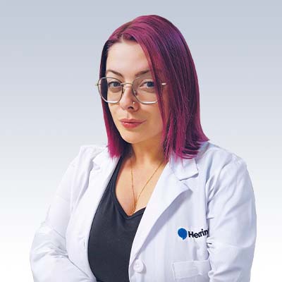 hearing care professional with magenta hair wearing a white coat