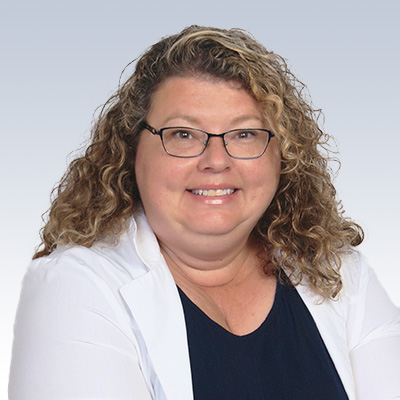 laura costa, hearing care professional with curly blonde hair wearing a white coat