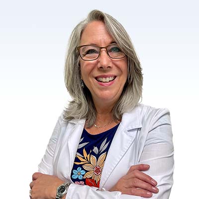 Lee Ann Youngblood, hearing care professional in a white coat, arms crossed, wearing a floral-patterned blouse.