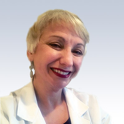 Mary Gootee wearing a white lab coat against a gradient blue background.