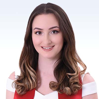 Miranda Velasquez wearing a white and red outfit with styled brown and blonde hair against a light gradient background.