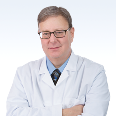 Hearing care professional in a white lab coat, arms crossed.