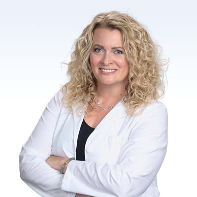 Hearing care professional with curly blonde hair wearing a white coat.