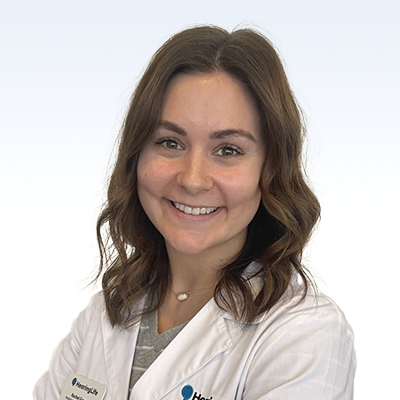 Hearing care professional wearing a white coat with wavy brown hair.