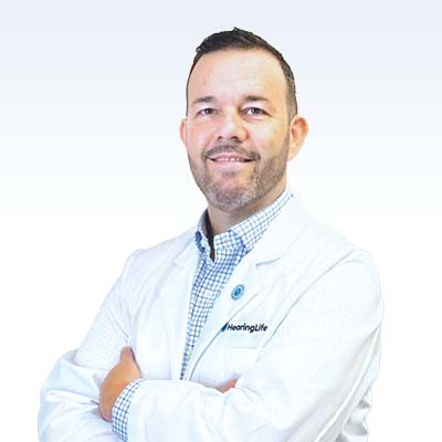 Ryan Jackson, hearing care specialist at HearingLife, wearing a white coat with arms crossed