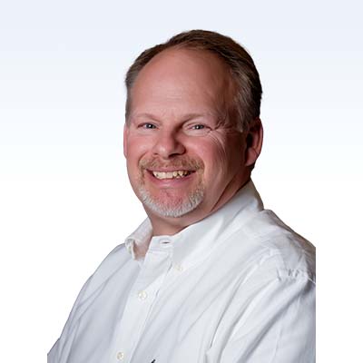 Sam Hamilton, hearing care professional wearing a white collared shirt, providing expert audiology services.