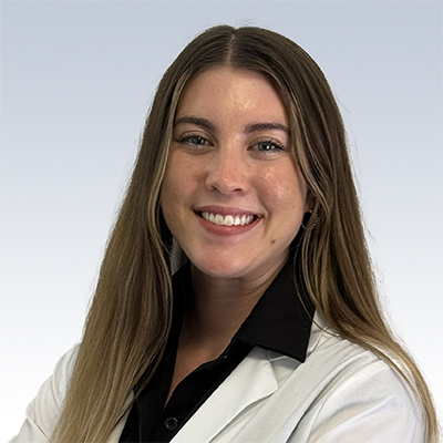 Shannon Shorter, hearing care specialist wearing a white coat and black shirt, smiling against a light gradient background.