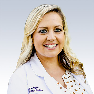 Hearing instrument specialist Solomiya Wright in a white lab coat.