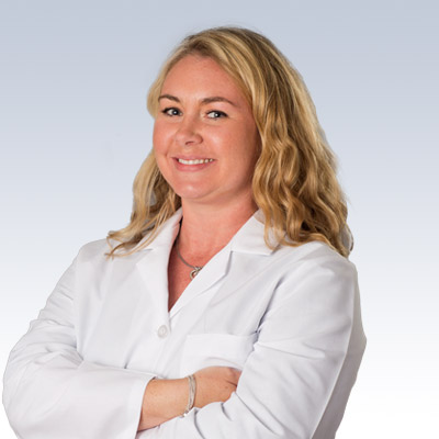 Stephanie Duncan, hearing care professional in a white coat, with arms crossed and wavy blonde hair.