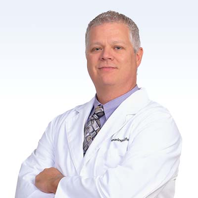 hearing care professional in a white coat with arms crossed