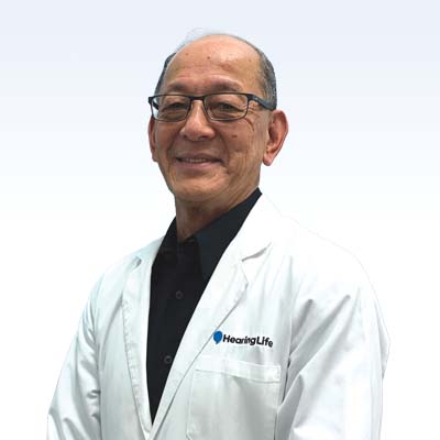 Hearing care specialist wearing a white lab coat with the HearingLife logo.