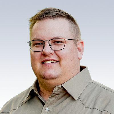Tyson Case wearing a beige collared shirt with a blurred face.