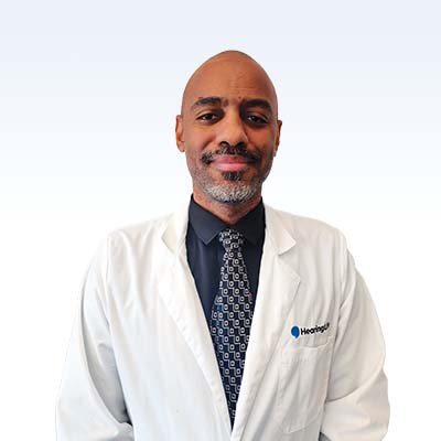 Hearing care professional wearing a white lab coat and patterned tie with a Hearing logo.