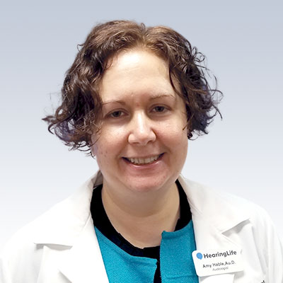 Amy Hable, Au.D., audiologist at HearingLife, wearing a white lab coat.
