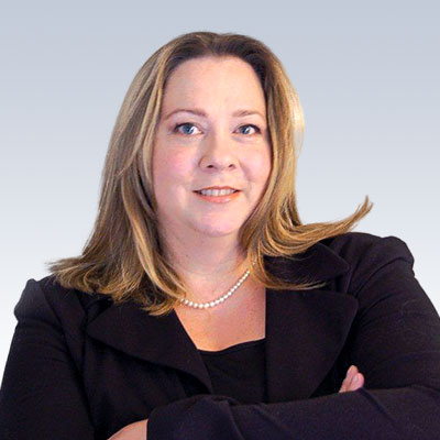 Andrea Lunney wearing a black blazer and pearl necklace against a light gradient background.