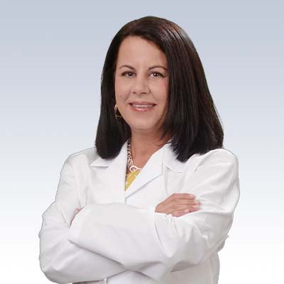 Angela Wright, hearing care professional, wearing a white coat with arms crossed against a neutral background.