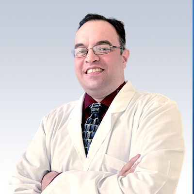 Anthony Nash wearing a white lab coat with arms crossed, representing a hearing care professional.