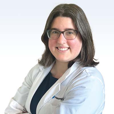 Ashley Helthall, hearing care professional in a white coat with the Heargly logo.