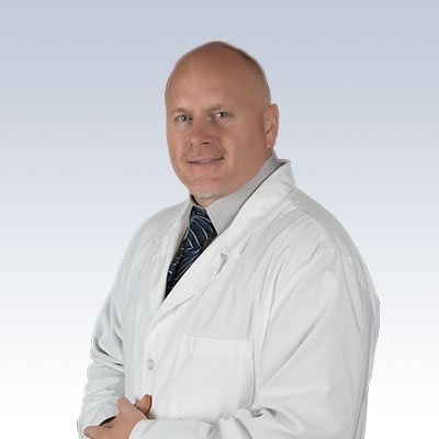 Chad Reust wearing a white lab coat against a gradient background.