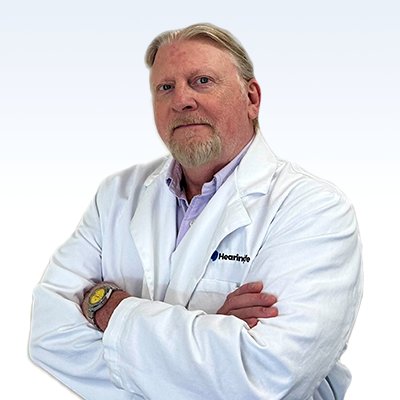 Christopher Bartlett, hearing care specialist wearing a white lab coat with arms crossed.