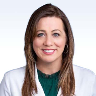 Christy Gartland, hearing care professional wearing a white coat and green blouse.