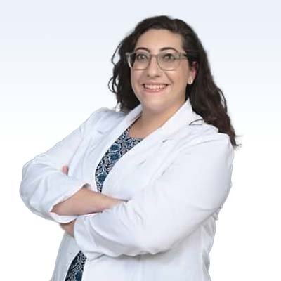 Hearing care professional Eleni Santarelli in a white lab coat.