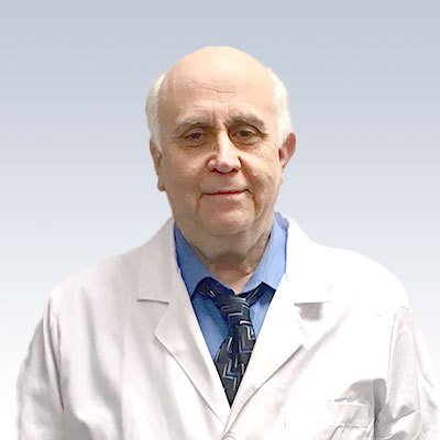 Gary Gromack wearing a white lab coat and blue shirt with a patterned tie.