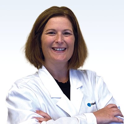 Hearing care specialist in a white lab coat with arms crossed.