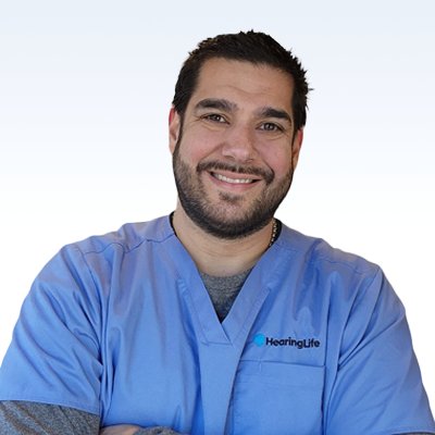 Hearing care professional in blue scrubs with a HearingLife logo.
