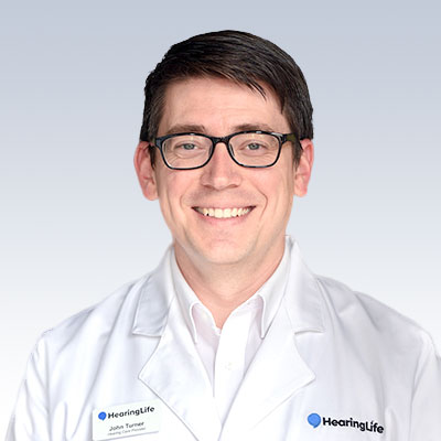 John Turner, hearing care specialist at HearingLife, wearing a white lab coat.